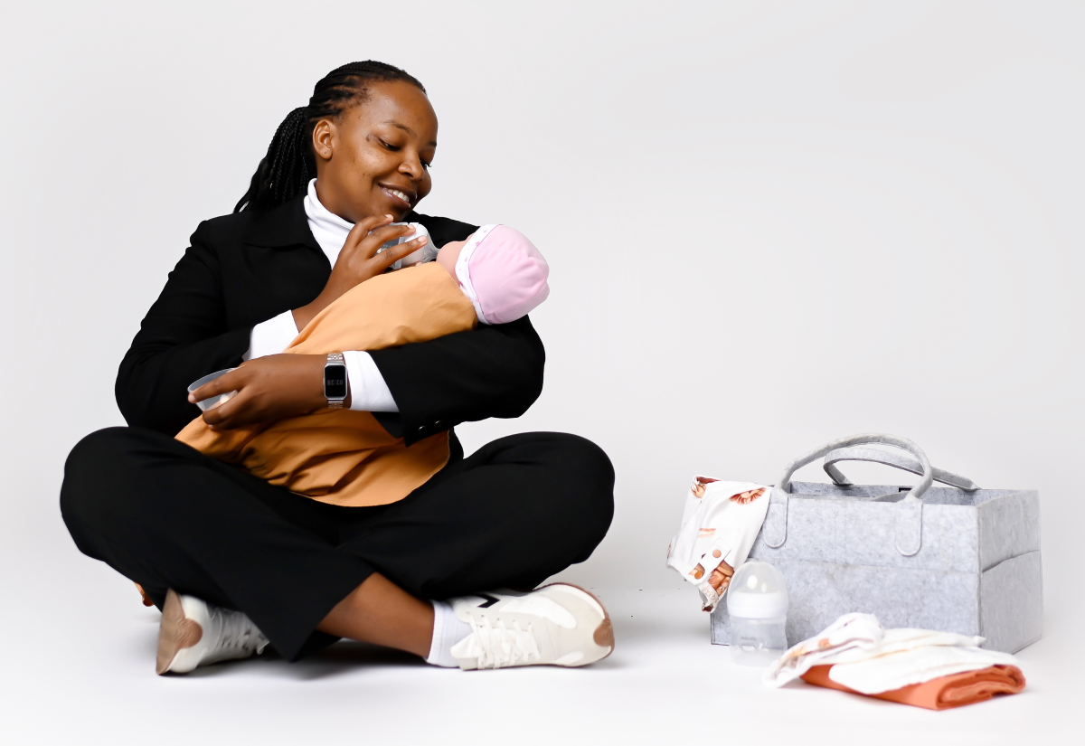 A woman happily holding a newborn baby wrapped in a blanket.